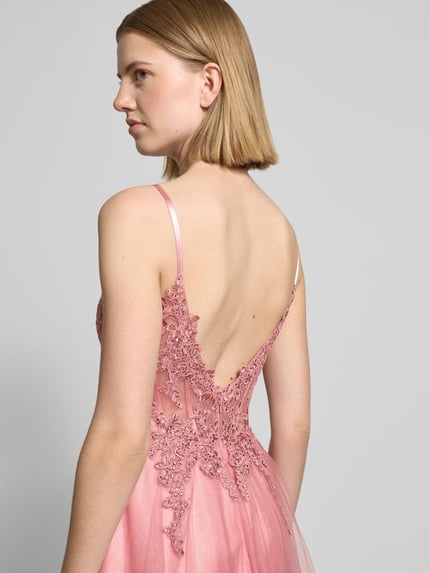 Vrouwenmodel draagt Maxikleid met Spitze und Gehschlitz van Luxuar in roze tule met kanten details, diepe rugdecolleté, getailleerd model, corsetjurk, spaghettibandjes, ruglengte maat 36: 121 cm, borstwijdte maat 36: 38 cm, detailopname rugaanzicht.