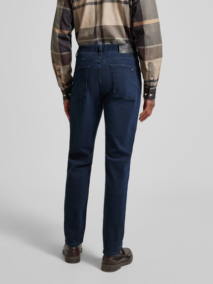 Męski model nosi Slim Fit Jeans aus Baumwoll-Mix Modell 'BLEECKER' von Tommy Hilfiger, z efektem melanżu, jeans, naszywka z logo, nity, 5 kieszeni, zapięcie na guzik i ukryty zamek, mieszanka bawełny, całkowity widok z tyłu.