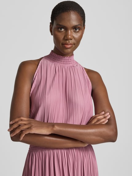 Frauenmodel trägt Plisseekleid mit Smok-Details Modell 'UMA' von Samsøe Samsøe, Material-Mix mit Stretch-Anteil, taillierter Schnitt, Stehkragen, Midikleid, rosa, Nahaufnahme Oberkörper.