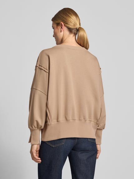 Vrouwenmodel draagt Oversized Sweatshirt aus reiner Baumwolle mit Statement-Print van miss goodlife in beige met ronde hals en elastische boorden, puur katoen, oversized fit, statementprint, dames sweatshirt, volledig lichaam achteraanzicht.