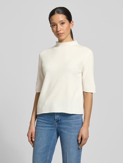Frauenmodel trägt Strickshirt aus Reine Wolle Modell 'Tumea' von Someday, Regular-Fit, Stehkragen, Rollsaum, helle Farbe, Ganzkörperansicht von vorne. Rückenlänge bei Größe 36: 52 cm, Ärmellänge bei Größe 36: 34 cm.