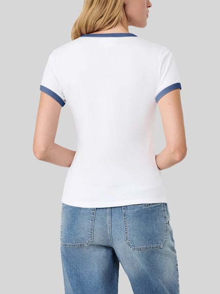 Kobiece modelka nosi biały t-shirt Regular Fit T-Shirt aus reiner Baumwolle - s.Oliver x Heidi Klum von s.Oliver RED LABEL, krótkie rękawy, granatowe wykończenia, niebieskie dżinsy, widok całej sylwetki z tyłu.