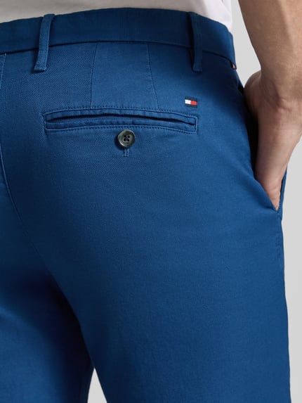 Mężczyznamodel nosi 'Slim Fit Chino aus Baumwoll-Mix' od Tommy Hilfiger, kolor niebieski, materiał piqué, krój slim fit, logo, detal tyłu, zbliżenie tyłu.