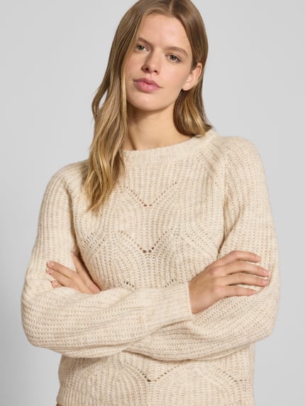 Frauenmodel trägt Relaxed Fit Strickpullover mit Woll-Anteil Modell 'GILA' von Only in Beige, grobe Strickstruktur, Nahaufnahme Oberkörper.