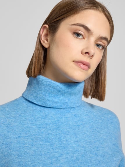 Frauenmodel trägt Regular Fit Rollkragenpullover aus Schurwoll-Mix von Marc O'Polo Denim in meliertem Hellblau, Strickstruktur, Nahaufnahme Oberkörper.