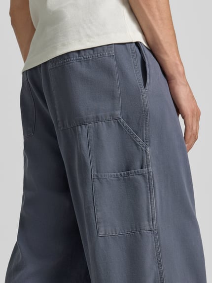 Männermodel trägt Wide Fit Jeans mit teilelastischem Bund Modell 'Lycaz' von American Vintage in Blau, Reine Baumwolle, Gesäßtaschen, Nahaufnahme Hüfte, Kontext: Herren Jeans, Knopf-Reißverschluss, Bundweite bei Größe M 39 cm, Innenbeinlänge 71 cm.