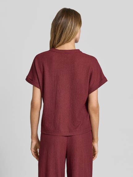 Frauenmodel trägt Regular Fit T-Shirt in Crinkle-Optik von s.Oliver RED LABEL in Dunkelrot, strukturierte Oberfläche, Ganzkörperansicht Rückansicht.