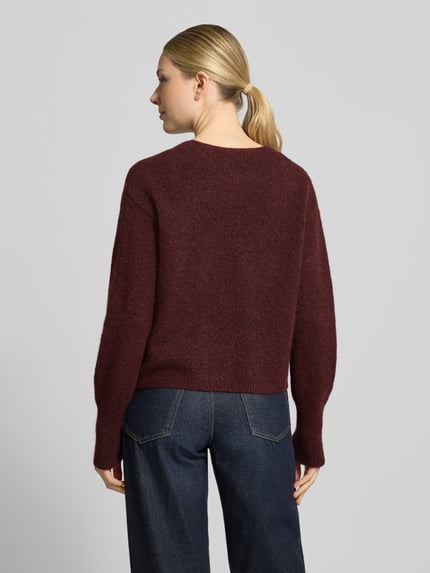Frauenmodel trägt Cardigan aus Wolle mit Logo-Stitching Modell 'Sirala' von HUGO, unifarben, strukturierte Strickoptik, Ganzkörperansicht Rückansicht.