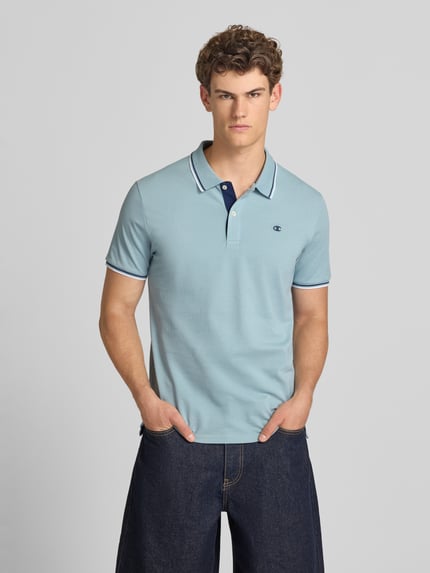 Männermodel trägt Slim Fit Poloshirt mit Label-Stitching von CHAMPION in Hellblau, Reine Baumwolle, Knopfleiste, Rückenlänge 73 cm, Ganzkörperansicht von vorne.