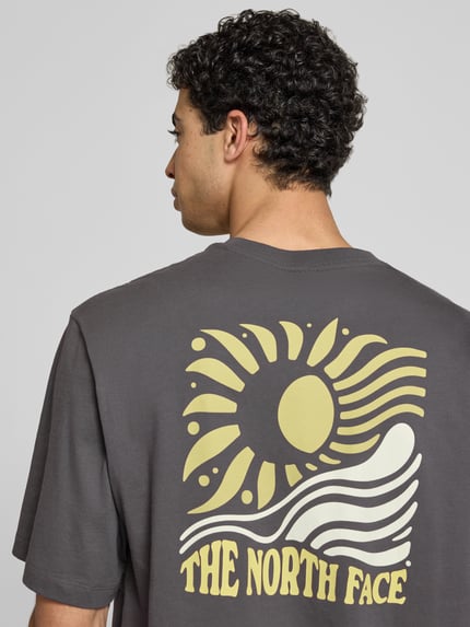 Männermodel trägt Oversized T-Shirt mit Logo-Print von The North Face in Dunkelgrau, reine Baumwolle, Rückansicht, Nahaufnahme Oberkörper.