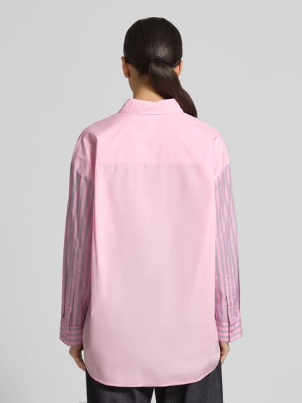 Vrouwenmodel draagt Relaxed Fit Hemdbluse uit pure katoen model 'JOLIVIA' van Essentiel Antwerp met gestreept allover-patroon en logostiksel, uni roze en roze geruit, overhemdkraag, lange mouw met manchet, rugpas en enkele knopenrij, rugaanzicht.