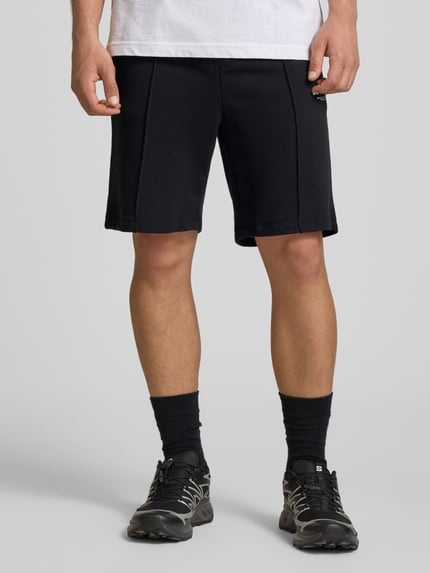 Männermodel trägt Sweatshorts mit Logo Modell 'KANE' von Jack & Jones aus Baumwoll-Mix, Schwarz, Relaxed-Fit, Ganzkörperansicht von vorne.