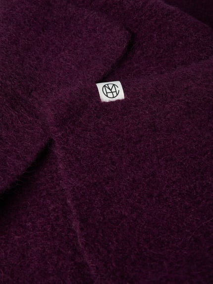 Produktfoto, Schal aus elastischem Woll-Mix mit Alpaka-Anteil Modell 'Hope' von MSCH Copenhagen, rechteckige Form, Label-Detail, tieflila Farbe, weiche Textur, Kontext: Damen Schal, Maße 41 x 105 cm