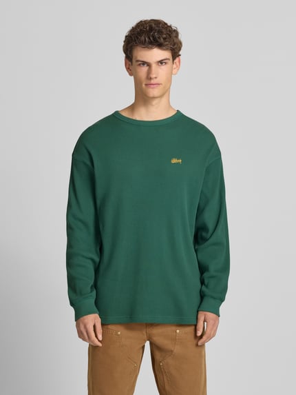 Männermodel trägt Longsleeve mit Logo-Stitching von BLKVIS in Grün, Strukturmuster, Reine Baumwolle, Loose-Fit, Rundhalsausschnitt, Ganzkörperansicht von vorne. Rückenlänge bei Größe S: 75 cm.