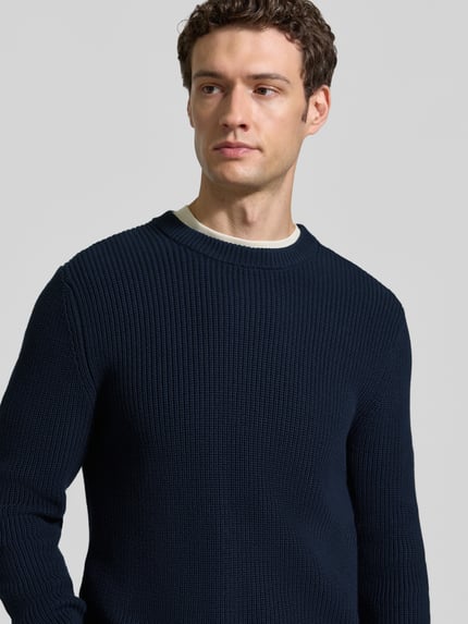 Männermodel trägt Regular Fit Strickpullover aus reiner Baumwolle von MCNEAL in Dunkelblau, sichtbare Struktur, Nahaufnahme Oberkörper.