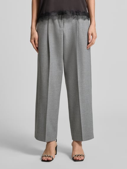 Frauenmodel trägt Regular Fit Bundfaltenhose mit Viskose-Woll-Anteil Modell 'SLOANNE' von SEDUCTIVE, graue Farbe, weite Passform, Nahaufnahme Unterkörper, Damen Bundfaltenhose von SEDUCTIVE.