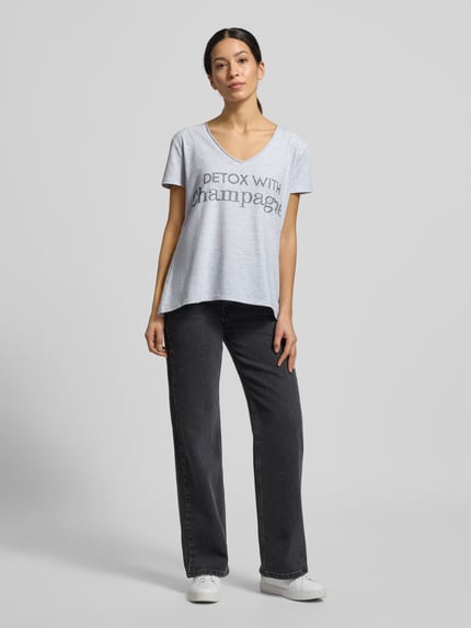 Modelka prezentuje T-shirt mit Label-Detail od miss goodlife, mieszanka bawełny i elastanu, luźny krój, dekolt w serek, długość tyłu 66 cm, widok całej sylwetki z przodu