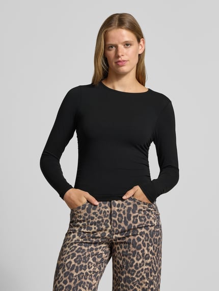Frauenmodel trägt Regular Fit Langarmshirt aus Baumwoll-Mix Modell 'MIRA' von ONLY in Schwarz, kombiniert mit Leopardenhose, Ganzkörperansicht von vorne, Damen Langarmshirt von ONLY.