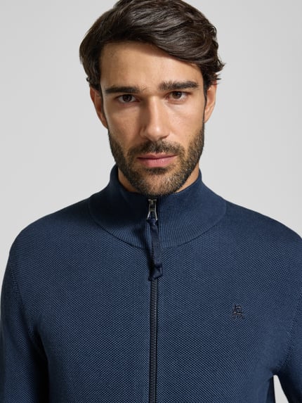 Männermodel trägt Strickjacke aus reiner Baumwolle mit Reißverschluss von LERROS, krój regular fit, granatowy, faktura two-tone, stójka, zamek, długość tyłu 67 cm, długość rękawa 50 cm, zbliżenie na górną część ciała.