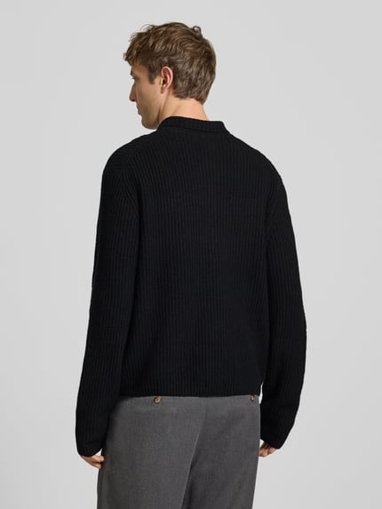 Männermodel trägt Strickjacke mit Zweiwege Reißverschluss von ONLY & SONS in Schwarz, gerippte Struktur, Relaxed Fit, Ganzkörperansicht Rückansicht.
