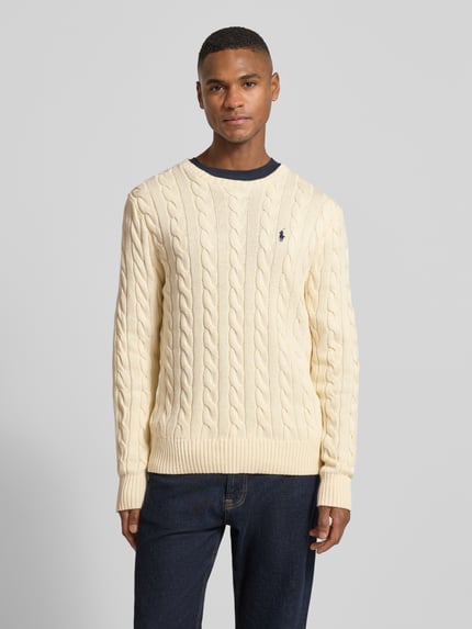 Männermodel trägt Strickpullover mit Label-Stitching von Polo Ralph Lauren, Reine Baumwolle, Regular-Fit, Rundhalsausschnitt, Gerippte-Abschlüsse, cremefarben, glatte und strukturierte Strickmuster, Rückenlänge 70 cm, Ärmellänge 73 cm, Ganzkörperansicht von vorne.