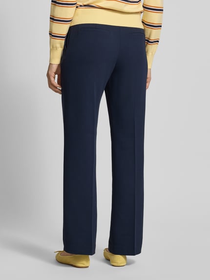 Vrouwenmodel draagt donkerblauwe dames broek met persplooien model 'LARA' van Samsøe Samsøe, regular fit, paspelzakken achter, bandwijdte maat S 39 cm, binnenbeenlengte maat S 85 cm. Volledige lichaamsaanzicht achterkant.