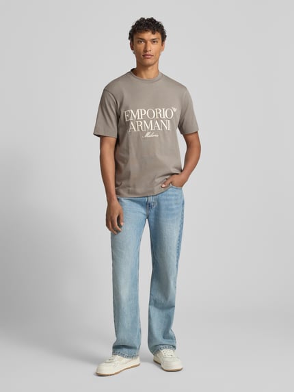 Männermodel trägt Herren T-Shirt mit Label-Stitching von Emporio Armani in Grau, reine Baumwolle, Regular-Fit, gerippter Rundhalsausschnitt, Ganzkörperansicht von vorne.