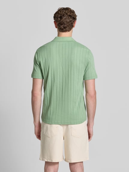 Männermodel trägt Regular Fit Poloshirt aus Baumwoll-Mix Modell 'TRAVIS' von SELECTED HOMME, Optik: Unifarben, Struktur, Ganzkörperansicht Rückansicht.