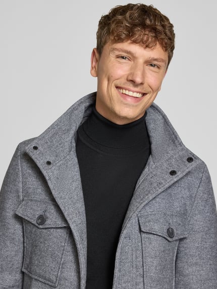 Männermodel trägt Jacke im 2-in-1-Look von Christian Berg Men aus grauem Material-Mix mit Woll-Anteil, Nahaufnahme Oberkörper.