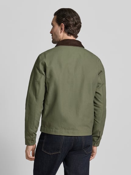 Męski model nosi Regular Fit Jacke mit Umlegekragen od MCNEAL, bawełna, kolor khaki, tył, krój regular fit, Ganzkörperansicht Rückansicht. Szerokość ramion w rozmiarze M: 48 cm, szerokość klatki piersiowej w rozmiarze M: 60 cm, długość pleców w rozmiarze M: 66 cm, długość rękawa w rozmiarze M: 68 cm, kieszeń na piersi, kieszenie boczne, zamek.