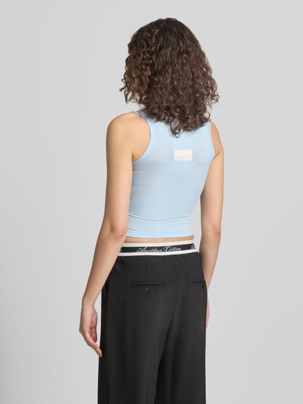 Frauenmodel trägt Slim Fit Top mit Logo-Detail von ANOTHER COTTON LAB, hellblau, elastischer Baumwoll-Mix, Rückansicht, Ganzkörperansicht.