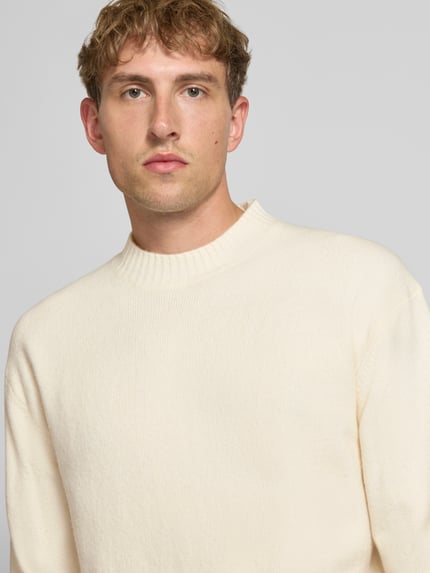 Männermodel trägt Relaxed Fit Strickpullover aus Material-Mix mit Baumwoll-Anteil von REVIEW, helle Farbe, Nahaufnahme Oberkörper.