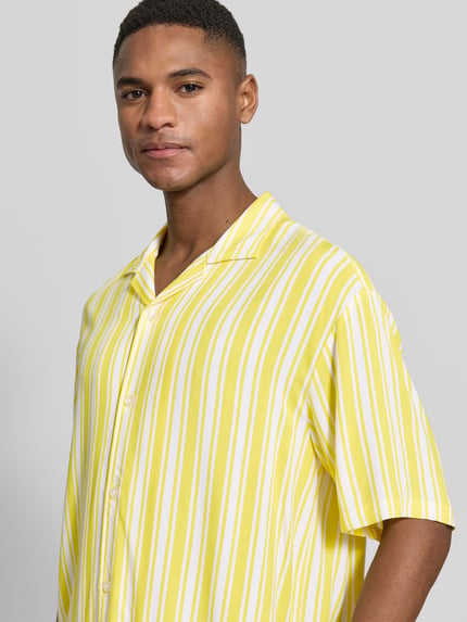 Männermodel trägt Regular Fit Freizeithemd aus reiner Viskose Modell 'Resort' von MCNEAL, gelb-weiß gestreift, Nahaufnahme Oberkörper.