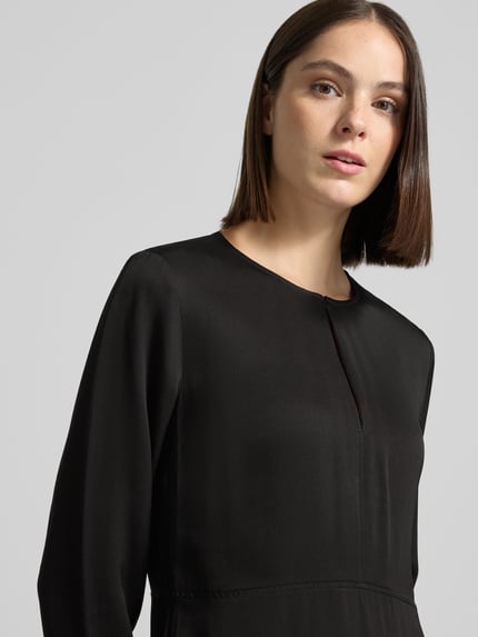 Frauenmodel trägt Minikleid mit Schlüsselloch-Ausschnitt von Selected in Schwarz, glatte Oberfläche, Damen Freizeitkleid, Nahaufnahme Oberkörper.