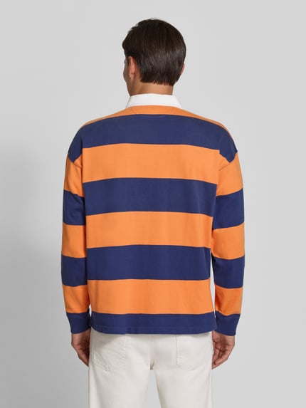 Männermodel trägt Oversized Pullover aus reiner Baumwolle Modell '6/1' von Polo Ralph Lauren in Orange und Dunkelblau, Ganzkörperansicht Rückansicht. Herren Pullover von Polo Ralph Lauren
