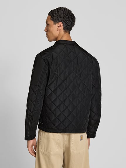 Männermodel trägt Regular Fit Jacke in Stepp-Optik von Replay, schwarze Farbe, Rautenstruktur, Rückansicht, Ganzkörperansicht Rückansicht. Herren Jacke mit Stehkragen, Druckknopfverschluss, Reißverschlusstaschen, Logo-Print, Maße: Rückenlänge 65 cm, Schulterbreite 29 cm, Brustweite 38 cm, Ärmellänge 63 cm.
