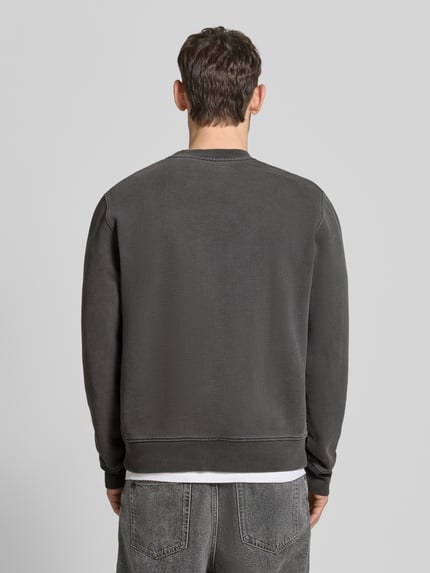 Mężczyzna nosi Sweatshirt mit Logo-Print Modell 'JOEL' od Samsøe Samsøe, bawełna, krój relaxed fit, ciemnoszary, widok całej sylwetki od tyłu.