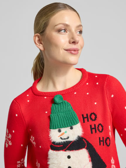 Frauenmodel trägt Pullover mit flauschigem Schneemann-Motiv von VERO MODA, mehrfarbig, Strickoptik, Rundhals, Nahaufnahme Oberkörper.