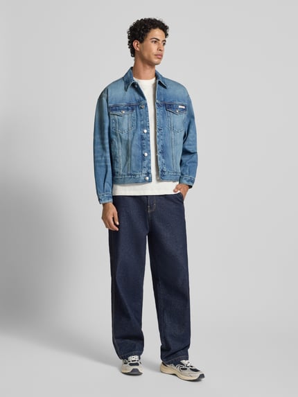 Männermodel trägt Jeansjacke mit Brusttaschen und Label-Detail von Calvin Klein Jeans aus Reine Baumwolle im Relaxed-Fit, Ganzkörperansicht von vorne.