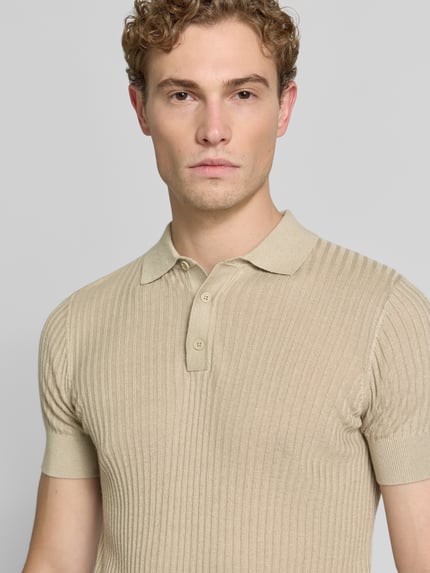 Männermodel trägt Slim Fit Poloshirt aus Viskose-Mix mit Leinen-Anteil von Antony Morato in Strick-Optik, beige, Nahaufnahme Oberkörper. Kontext: Herren Poloshirt, Polokragen, Rückenlänge bei Größe M 70 cm.