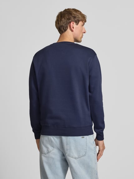 Männermodel trägt Regular Fit Sweatshirt aus Baumwoll-Mix mit Label-Detail von Alpha Industries in Dunkelblau, Rückenansicht, Herren Sweatshirt, elastische Abschlüsse, 67 cm Rückenlänge, 63 cm Ärmellänge.