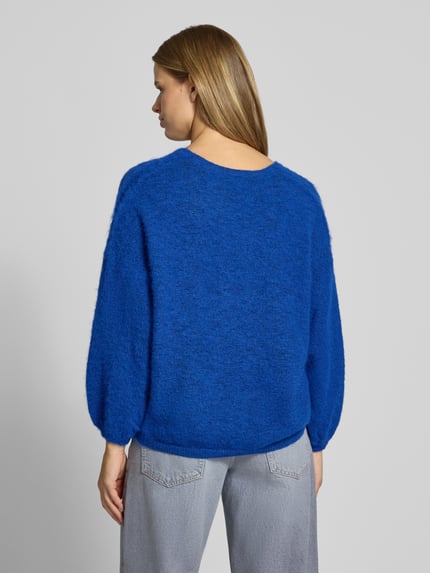 Frauenmodel trägt Pullover mit V-Ausschnitt Modell 'PCALLIE' von PIECES in Melange-Optik, langarm, gestrickt, Ganzkörperansicht Rückansicht.