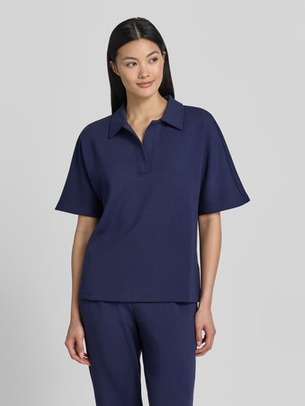 Modelka kobieca nosi Regular Fit Poloshirt mit V-Ausschnitt von Christian Berg Woman, granatowy, materiał z domieszką modalu, półrękaw, gładka tekstura, widok całej sylwetki z przodu.