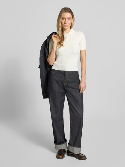 Frauenmodel trägt Slim Fit Strickpullover aus Viskose-Mix Modell 'Sareplette' von HUGO, Strickoptik, Struktur-Muster, Polokragen, V-Ausschnitt, Kurzarm, Materialverarbeitung Strick, Farbe creme, Ganzkörperansicht von vorne.