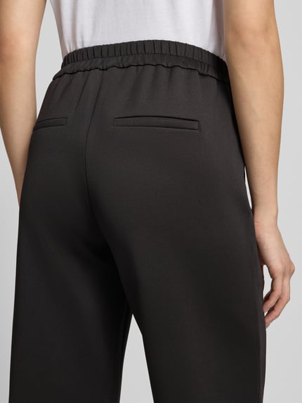 Frauenmodel trägt Flared Fit Hose mit teilelastischem Bund von COMMA, elastyczna mieszanka materiałów, kieszenie z tyłu, kolor czarny, Szerokość w rozmiarze 36: 38 cm, Długość wewnętrzna nogawki w rozmiarze 36: 69 cm, Ganzkörperansicht Rückansicht