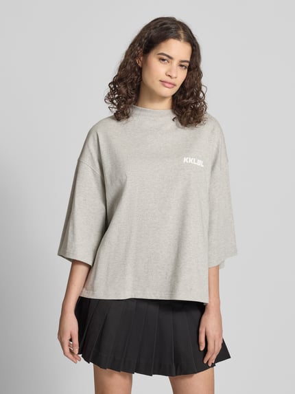 Vrouwenmodel draagt Oversized T-Shirt mit Rundhalsausschnitt van Karo Kauer, grijs, katoen, oversized fit, cropped, labelprint, voorkant, bovenlichaam close-up.