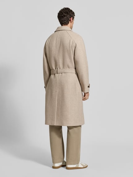 Männermodel trägt Mantel aus Woll-Mix mit Bindegürtel von MCNEAL in Beige, Pattentaschen, Ärmelriegel, strukturierte Oberfläche, Ganzkörperansicht Rückansicht.