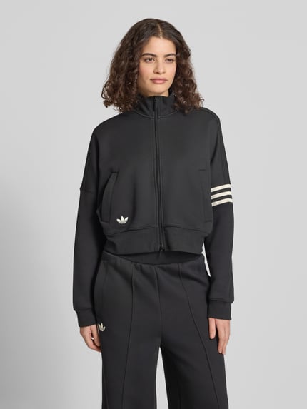 Frauenmodel trägt Regular Fit Sweatjacke aus Baumwoll-Mix von adidas Originals, Optik: Unifarben, Logo-Stitching, Stehkragen, Reißverschluss, Langarm, Ärmelabschluss und Rumpfabschluss gerippt, seitliche Eingrifftaschen, Materialverarbeitung: Sweat, Material: Baumwoll-Mix, Ganzkörperansicht von vorne.