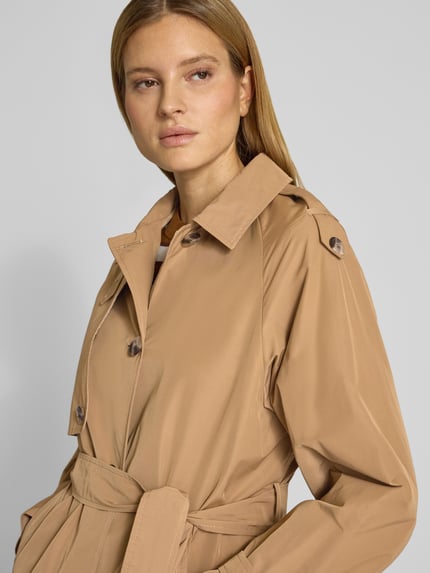 Frauenmodel trägt Trenchcoat mit Bindegürtel von Fuchs Schmitt in Beige, Material-Mix mit Baumwoll-Anteil, Regular-Fit, Umlegekragen, Knopfleiste, Nahaufnahme Oberkörper. Rückenlänge bei Größe 36: 124 cm, Schulterbreite: 42 cm, Brustweite: 38 cm, Ärmellänge: 42 cm.