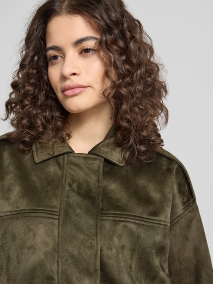Frauenmodel trägt Regular Fit Blouson in Wildlederoptik Modell 'AMBER' von Only in Olivgrün mit Umlegekragen, Nahaufnahme Oberkörper.